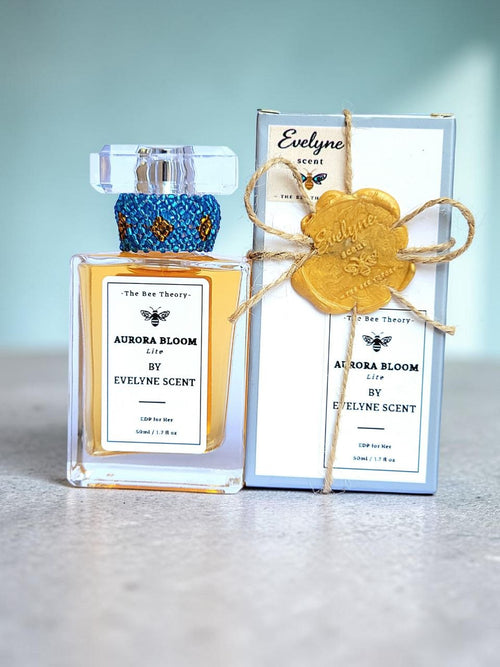 Perfume bottle and packaging with 'Aurora Bloom' and 'Evelyn Scent' branding on a light blue background.